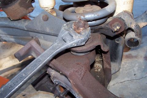 1990 Ford Bronco - A silver adjustable wrench is shown tightening a rusty nut on a suspension component of a vehicle. The vehicle appears to be a truck or SUV…
