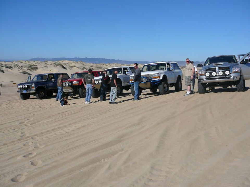 Group of people with off-road vehicles on sand dunes.