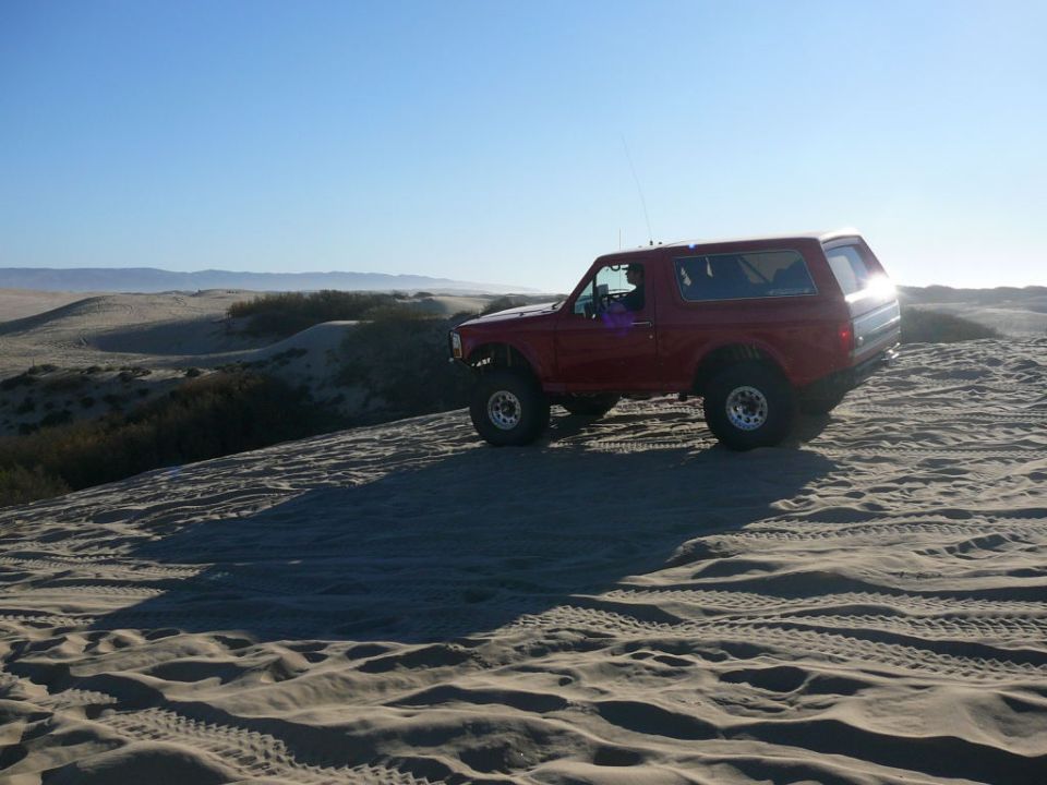 Red Ford Bronco on a sand dune.