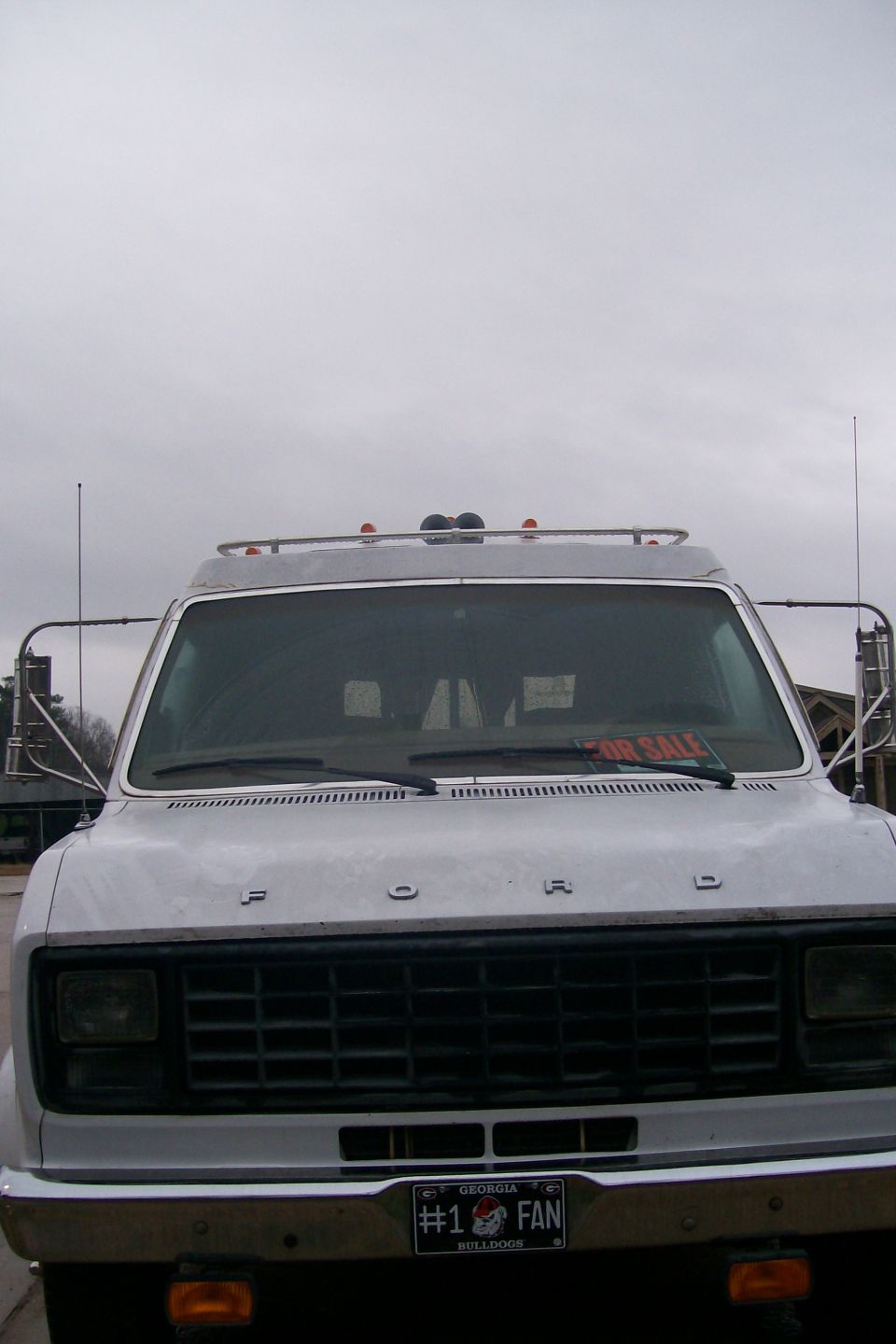 Front view of a white Ford van with a Georgia Bulldogs license plate and a "FOR SALE" sign.
