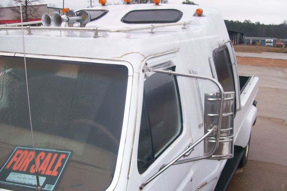 White dually pickup cab with raised roof, amber clearance lights, air horns, tow mirrors