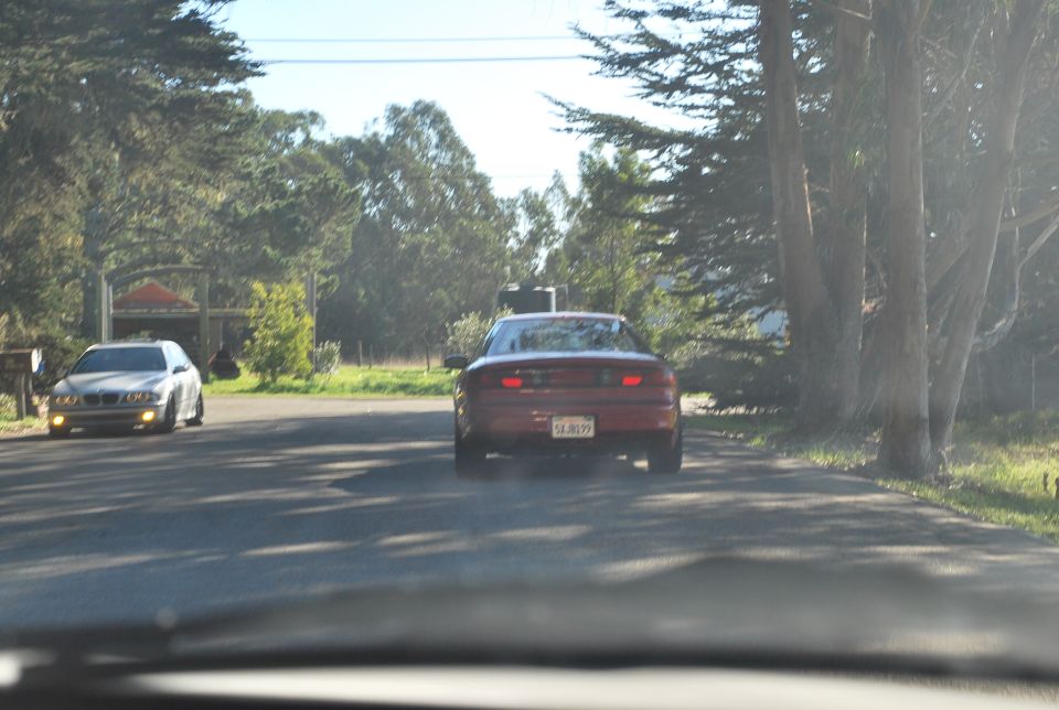 Red 1994 Ford Probe driving on a road with trees and another car.