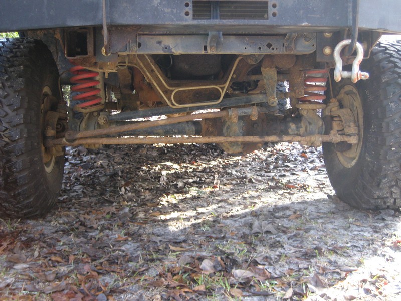 Underside front axle of a lifted 4x4 with red coil springs and a bow shackle