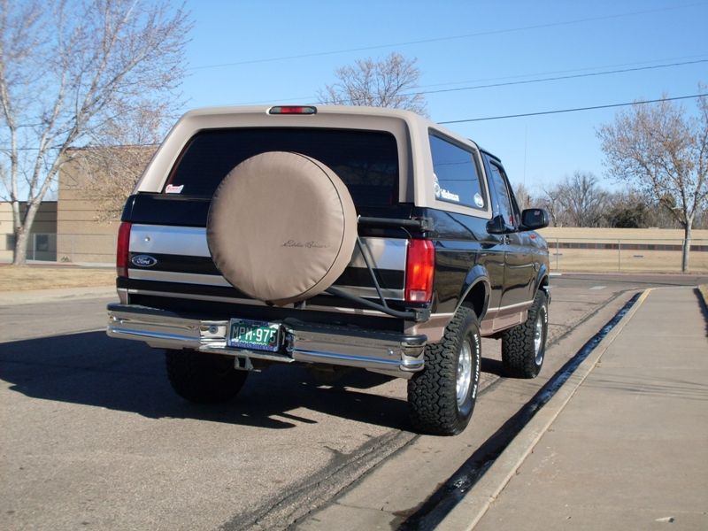 Rear view of a black 1996 Ford Bronco with a tan top and spare tire cover.