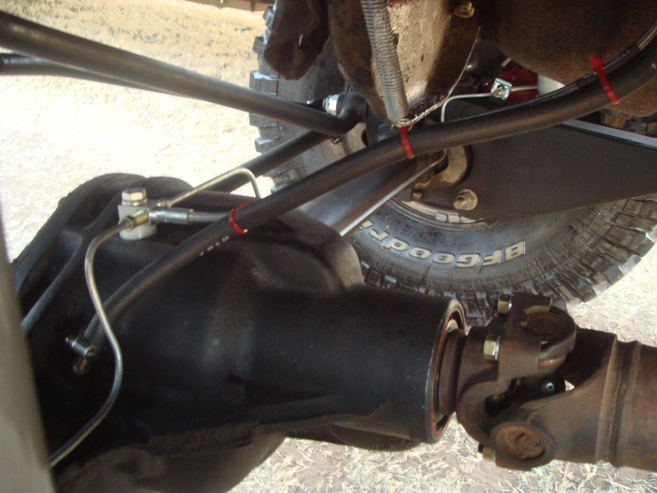 Close-up of a vehicle's rear differential, driveshaft, and suspension components.