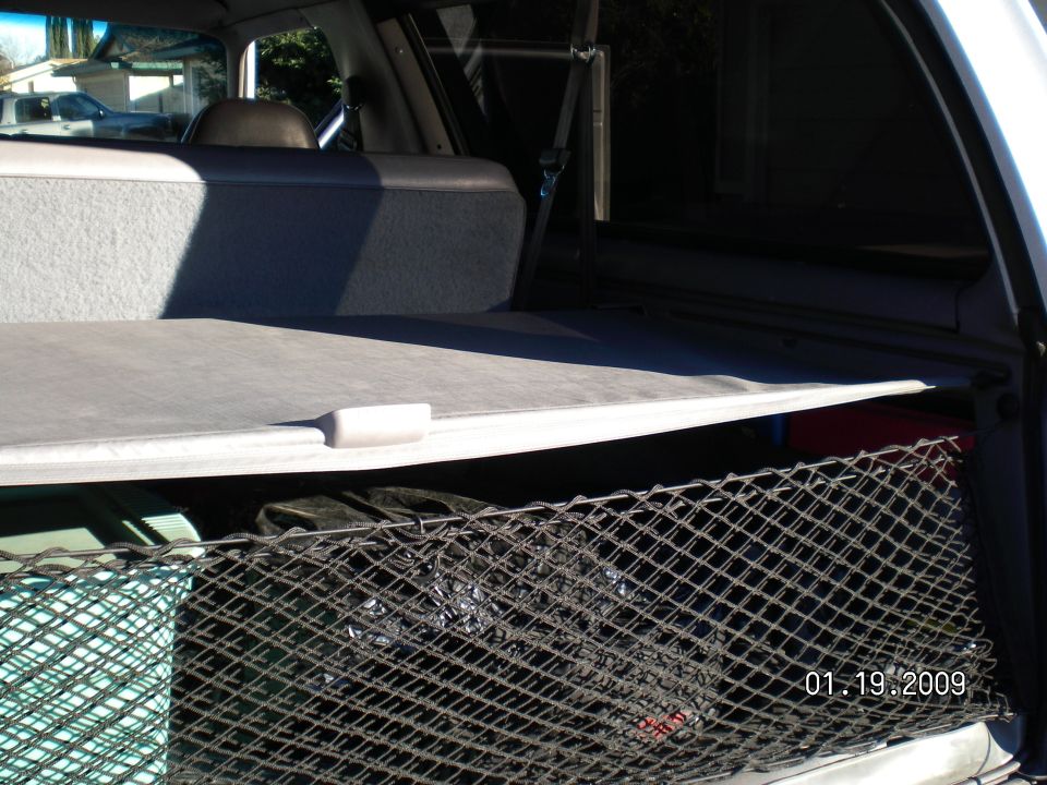 Gray cargo cover and black cargo net in the open rear cargo area of an SUV