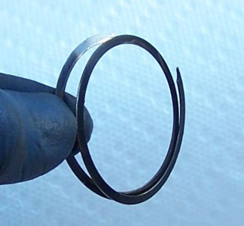 1990 Ford Bronco - A gloved hand holds a pair of metal piston rings, one slightly separated from the other.