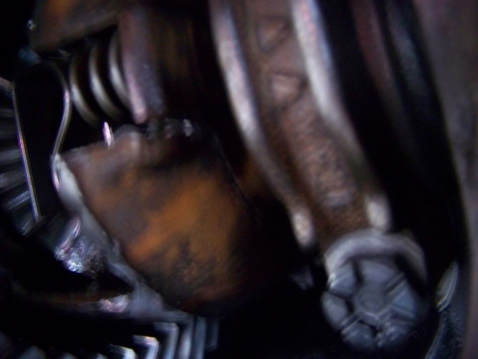 Close-up of engine parts: spring, lever, and bolt.