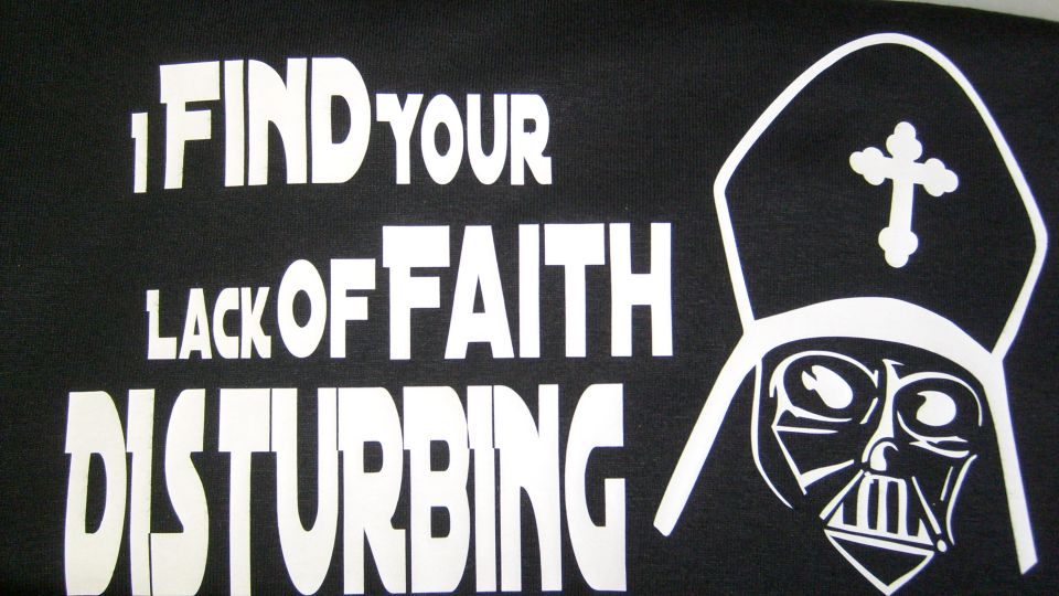 Black t-shirt with white text: "I FIND YOUR LACK OF FAITH DISTURBING" and Darth Vader in a religious headdress.