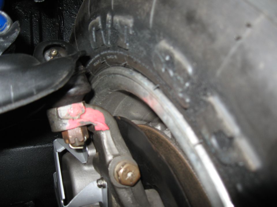 Close-up of a car tire and red brake caliper.