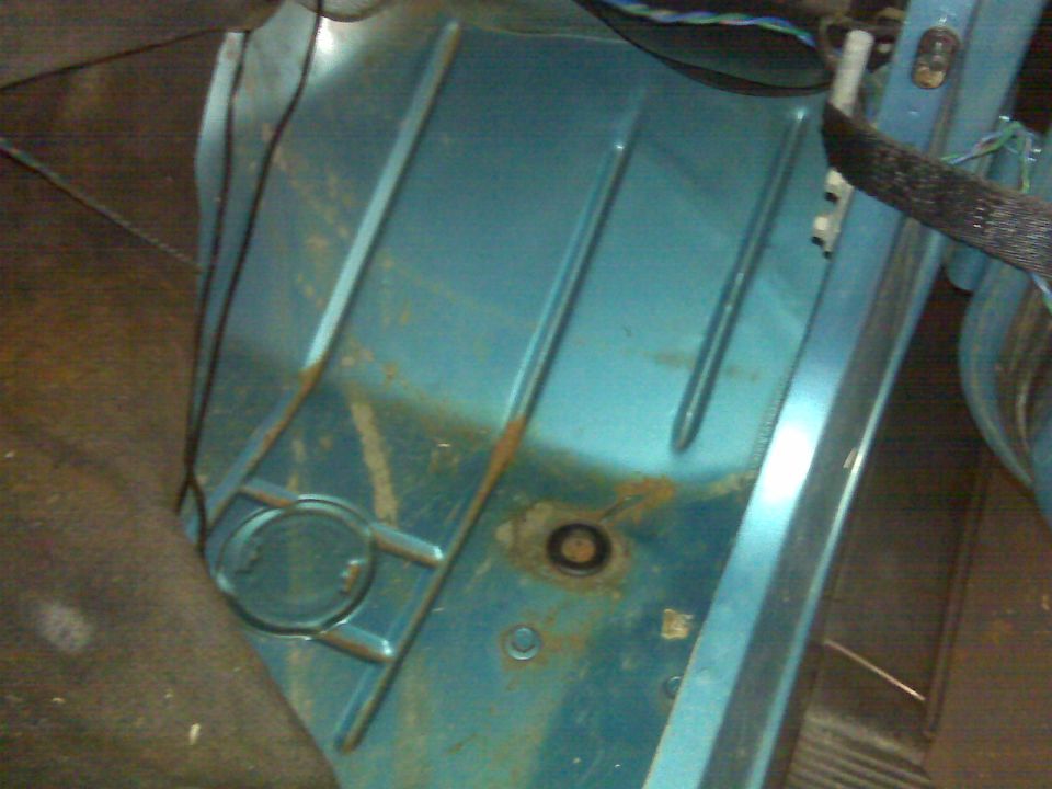 Underside of a teal vehicle with rust and wiring.