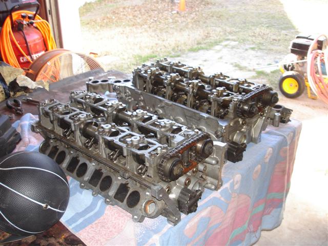 Two engine cylinder heads on a table with a basketball.
