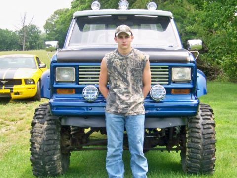 1983 Ford Ranger - A lifted blue pickup truck with large tires is parked on grass, with a yellow Mustang in the background.