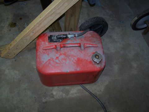 2007 Ford Bronco - A red fuel tank with a black handle and cap is shown resting on a concrete floor. A wooden support beam is positioned above and behind the…