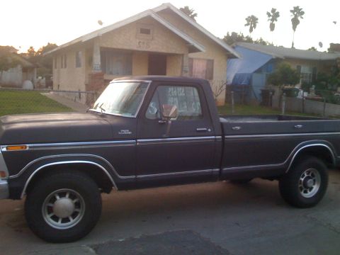 1979 Ford Bronco - A dark 1979 Ford Bronco pickup truck is parked in front of a house.