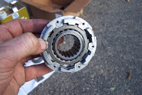 1990 Ford Bronco - A person holds a metal automotive part, likely a locking hub, with visible splines and gear teeth.