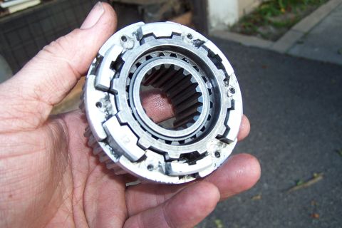 1990 Ford Bronco - A hand holds a metal transfer case component, showing its internal splines and external gear teeth.