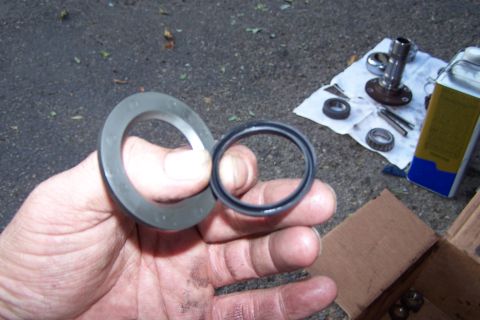 1990 Ford Bronco - Close-up of a ball joint seal and bearing, with related automotive parts laid out on a cloth.