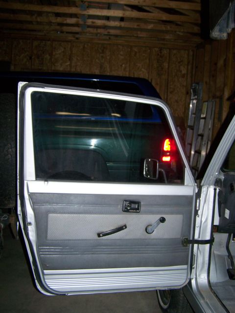 1988 Suzuki Samurai - The interior door panel of a Suzuki Samurai is shown, with another vehicle reflected in the window.