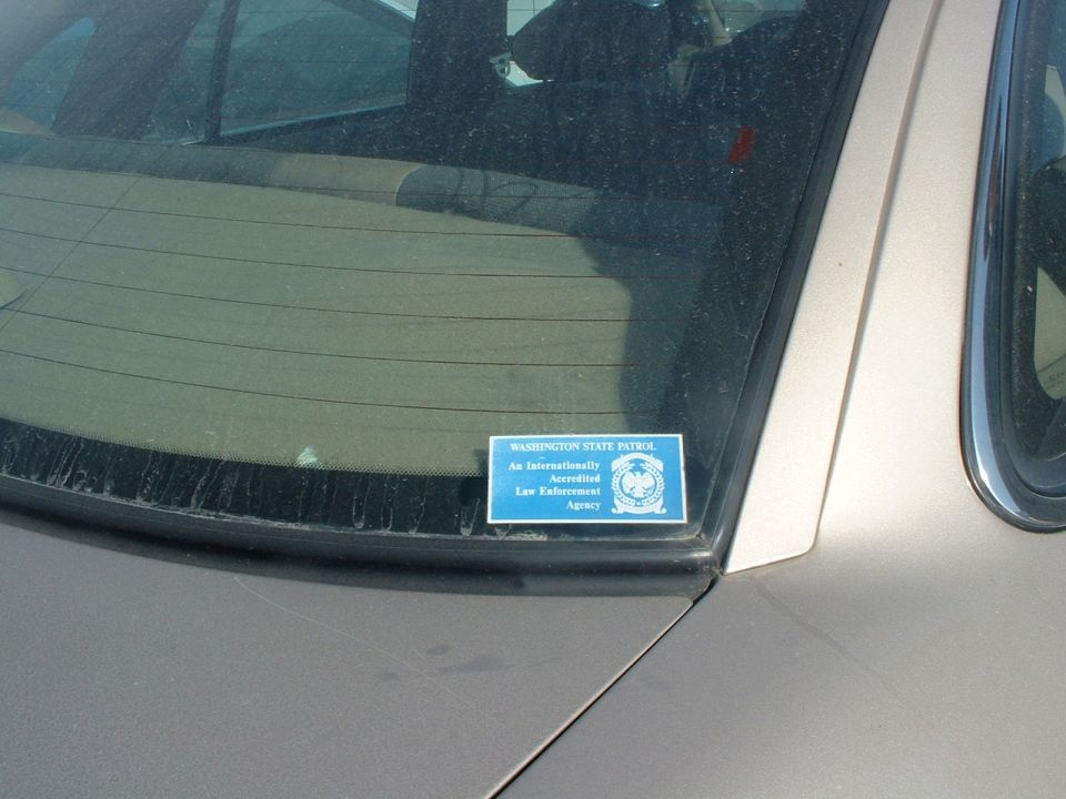 Washington State Patrol accreditation decal on rear window of tan sedan