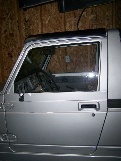 1988 Suzuki Samurai - Side view of a silver 1988 Suzuki Samurai, showing the interior and door panel.
