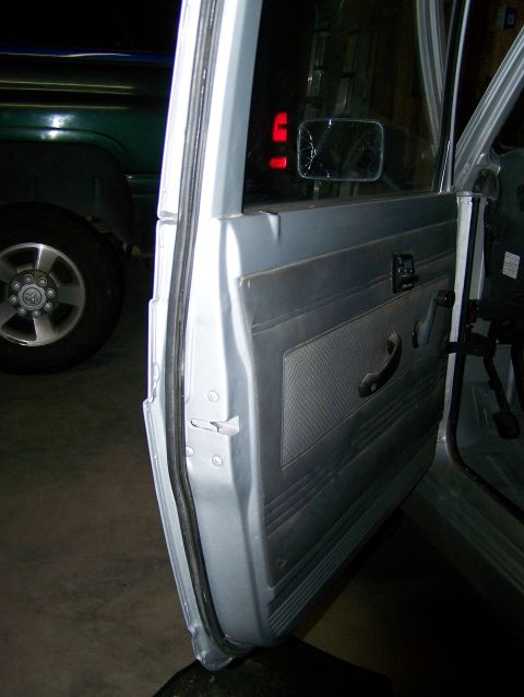1988 Suzuki Samurai - Close-up of a vehicle's interior door panel and frame, with another vehicle in the background.