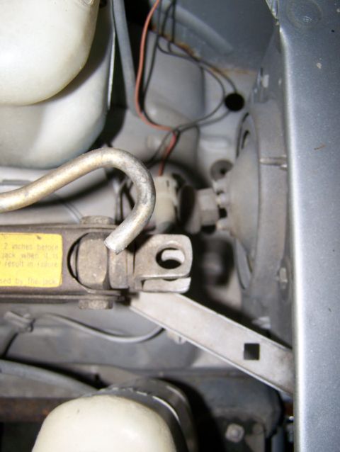 1988 Suzuki Samurai - Close-up of a car jack and wiring, with a yellow warning sticker visible.