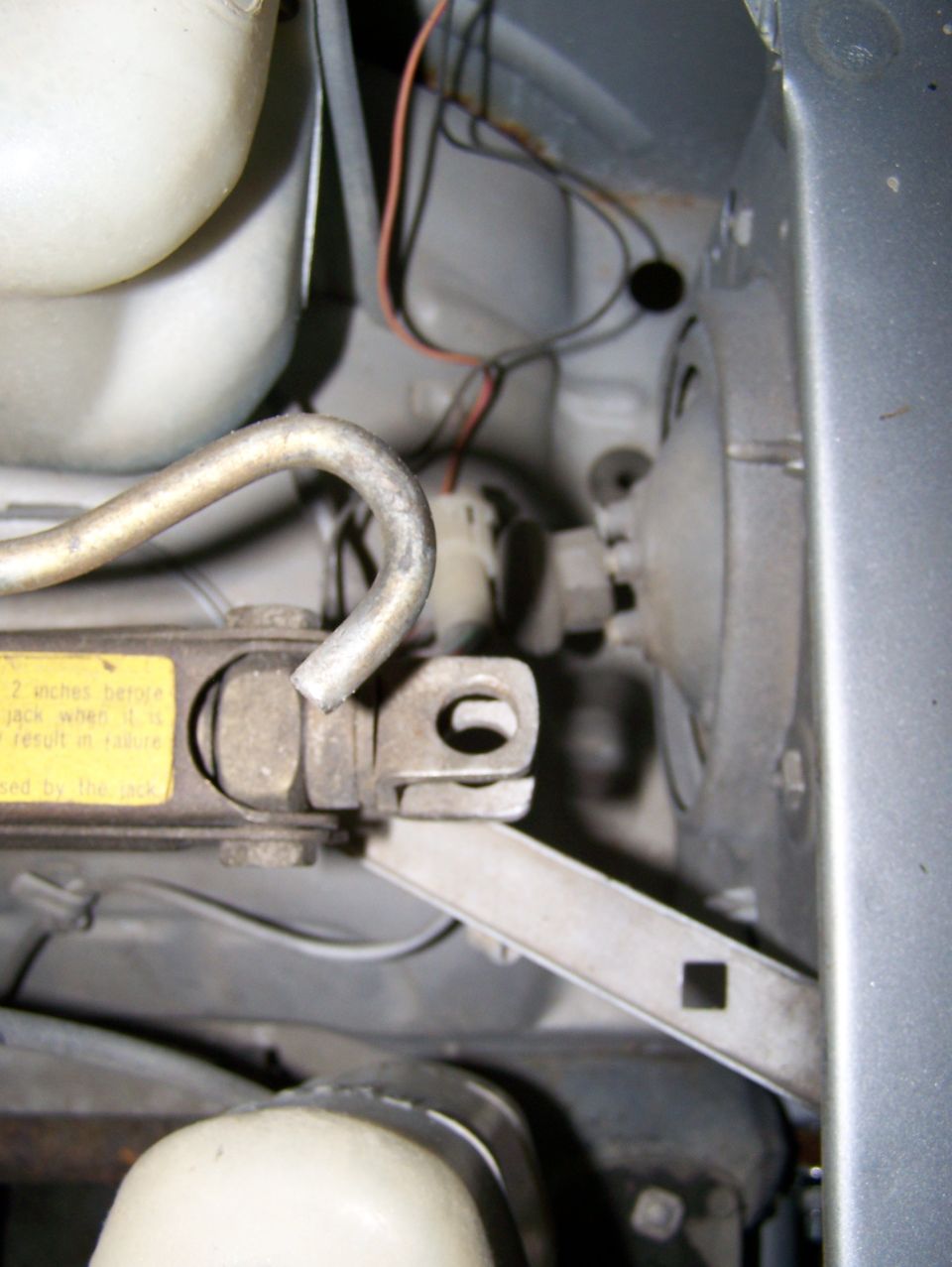 Car jack with yellow warning sticker and wiring