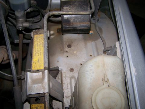 1988 Suzuki Samurai - Scissor jack and fluid reservoir visible in the engine bay of a vehicle.