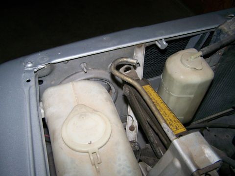 1988 Suzuki Samurai - Close-up view of the engine bay of a 1988 Suzuki Samurai, showing various fluid reservoirs and a jack.