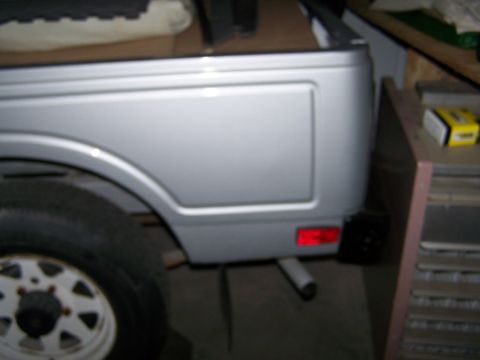 1988 Suzuki Samurai - Rear view of a silver 1988 Suzuki Samurai, showing the quarter panel, taillight, and exhaust.