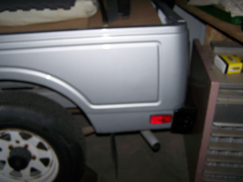 Silver 1988 Suzuki Samurai rear quarter panel with red taillight and exhaust pipe