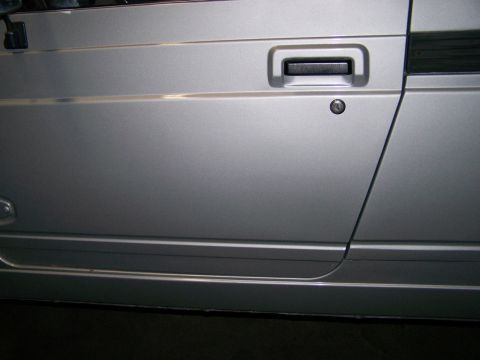 1988 Suzuki Samurai - Close-up of the side door and rocker panel of a silver 1988 Suzuki Samurai.