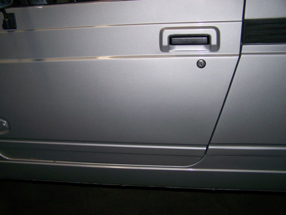 Silver 1988 Suzuki Samurai door with black handle and lock cylinder, side view