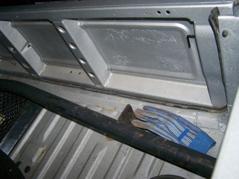 1988 Suzuki Samurai - The interior cargo area shows a roll bar and a pair of blue work gloves resting on the bed liner.