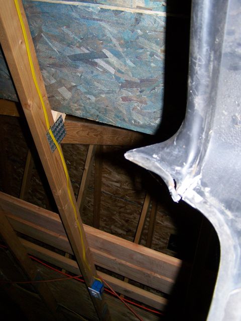 1988 Suzuki Samurai - Damaged black plastic trim piece in an attic space with visible wood framing and wiring.