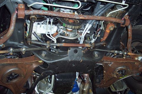 2001 Ford Crown Victoria - The undercarriage of a vehicle is shown, with focus on the engine and suspension parts, some of which are heavily rusted.