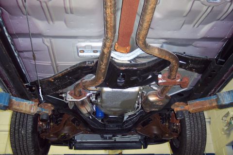 2001 Ford Crown Victoria - The undercarriage of a vehicle is shown, lifted for inspection of its exhaust and drivetrain components.