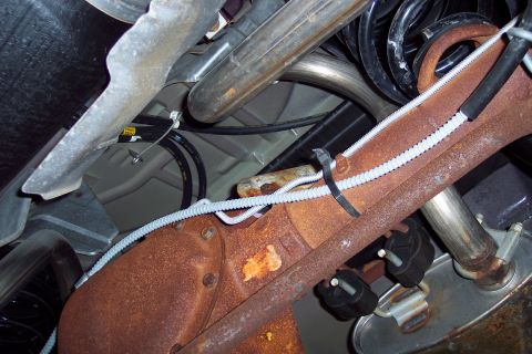2001 Ford Crown Victoria - Underside view of a vehicle's rear axle and exhaust system, showing rusty components and wiring.