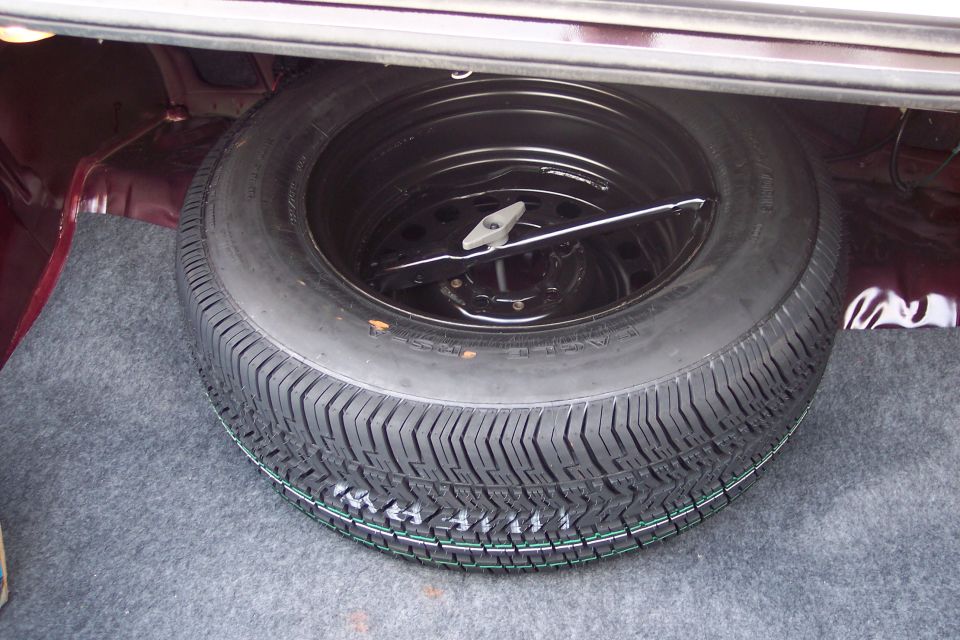 Spare tire and jack in the trunk of a dark red car