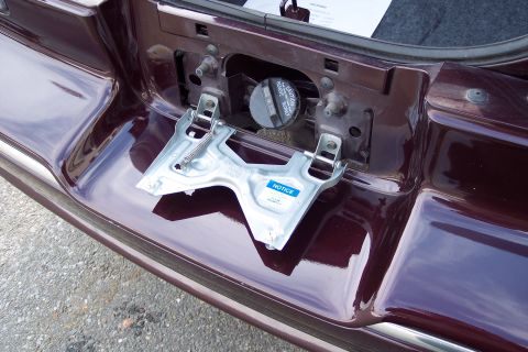 2001 Ford Crown Victoria - The fuel filler door area of a car, with a notice sticker on a metal bracket.