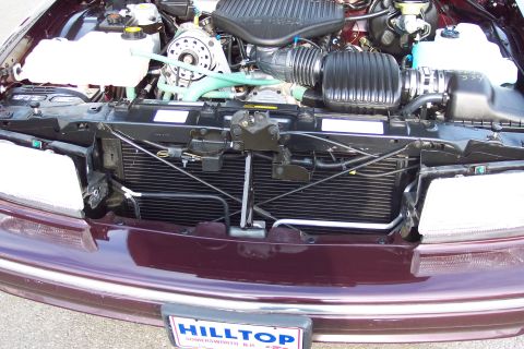2001 Ford Crown Victoria - The engine bay of a maroon 1996 Chevrolet Caprice is visible, with the radiator and various engine parts clearly displayed.