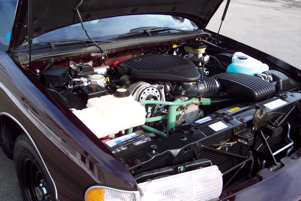 Engine bay of a 1996 Chevrolet Caprice with the hood open, showing the V8 engine, air intake, battery, and coolant reservoir