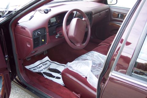 2001 Ford Crown Victoria - The interior of a maroon 1996 Chevrolet Caprice Classic sedan, plush seats and a dashboard with a digital display.