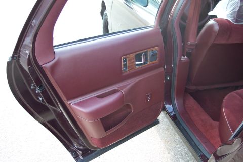 2001 Ford Crown Victoria - Interior view of a maroon door panel with wood trim and power controls, showing the seat and seatbelt.
