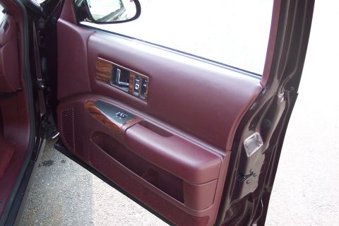 2001 Ford Crown Victoria - Close-up of a car's interior door panel, showing the maroon upholstery and wood accents.