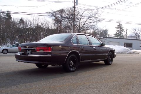2001 Ford Crown Victoria - A dark sedan is parked on an asphalt surface with a light-colored sedan in the background.
