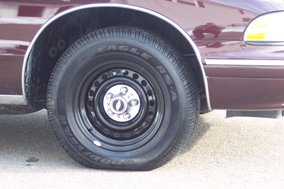Close-up of a black steel wheel with a chrome center cap on a maroon car