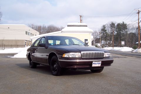 2001 Ford Crown Victoria - A maroon 1990s Chevrolet Caprice sedan is parked outside on a cold, snowy day.