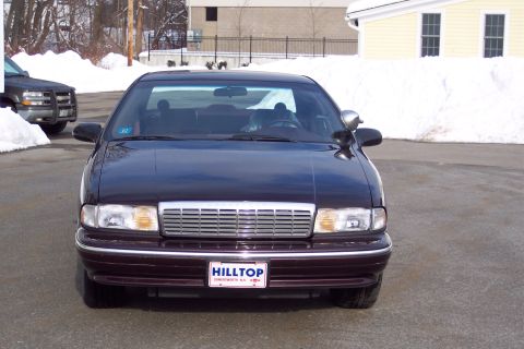 2001 Ford Crown Victoria - A dark sedan is parked outside in the snow, with another vehicle visible to the left.